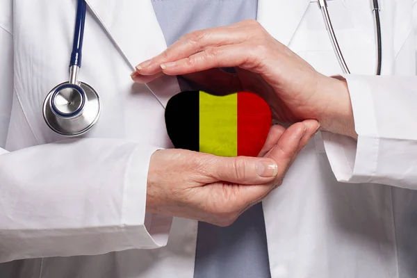 持有比利时国旗背景心脏的比利时医生 保险和医药概念 — 图库照片