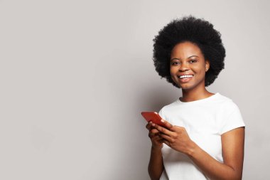 Cep telefonuyla gülümseyen siyah bir kadının portresi.