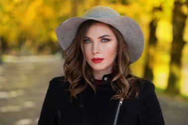 Sonbahar manzarasında klasik şapka takan güzel bir bayan.