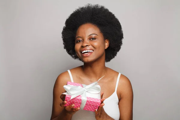 Attractive black woman holding pink present gift box on white background