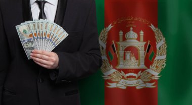 Afganistan 'ın bayraklarına karşı 100 dolarlık banknotlar tutan iş adamı. 