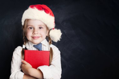 Noel Baba şapkalı, kitaplı şirin bir kız. Boş karatahta arkaplan üzerinde kopya alanı olan Mutlu Çocuk