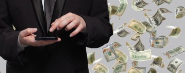 İşadamı cep telefonuyla çalışıyor. Para altında. Yağmur, gri arka planda izole edilmiş.