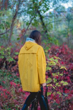 Sırt çantalı genç bir kadın parkta yürüyor.