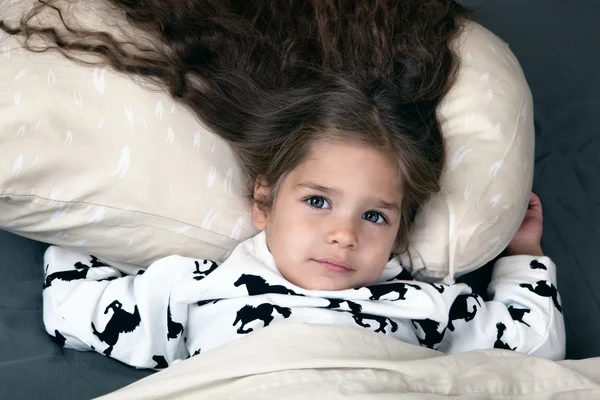 Kleines Mädchen mit köstlichen Haaren im Bett — Stockfoto