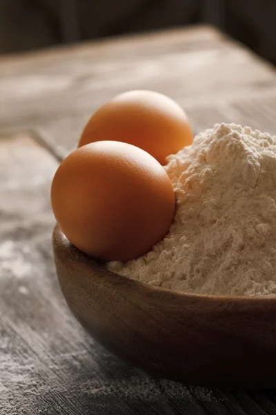 Mehl und Eier auf einem Holztisch — Stockfoto