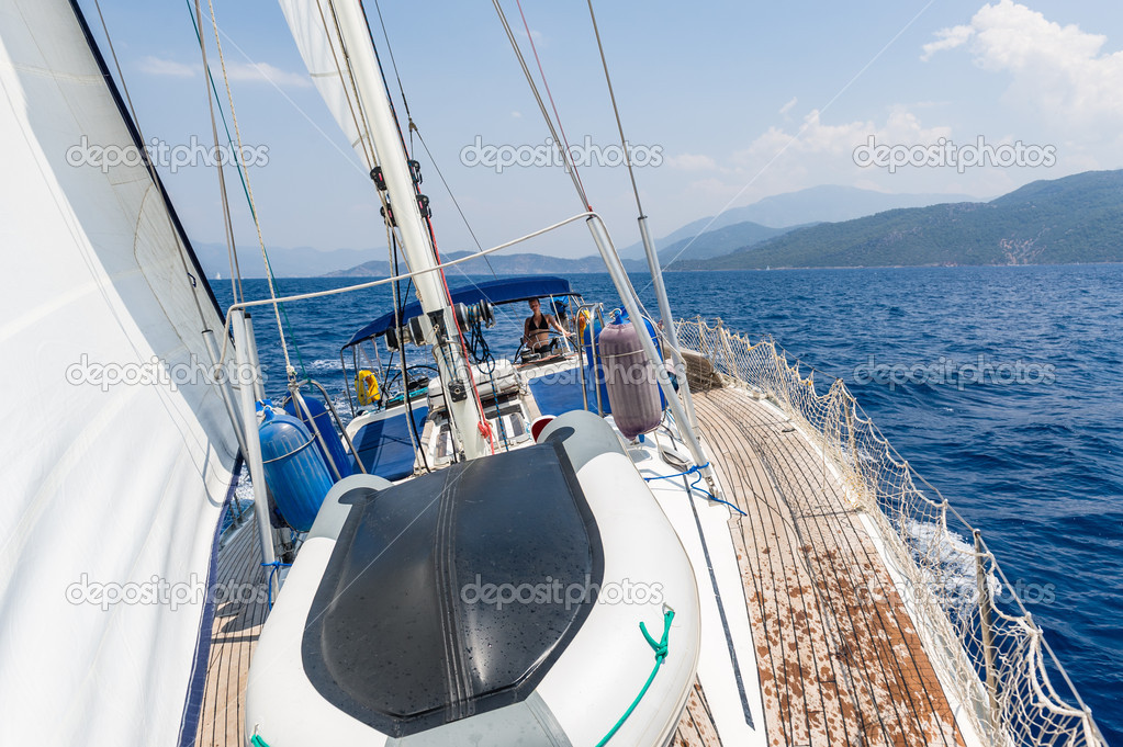 Sailing cruising yacht with women on the helm