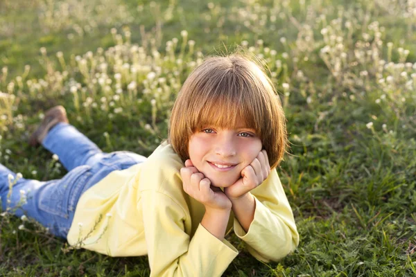 Sorridente giovane ragazzo sdraiato sull'erba — Foto Stock