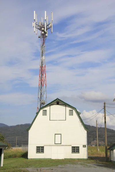 Uma torre de transmissão e um celeiro — Fotografia de Stock