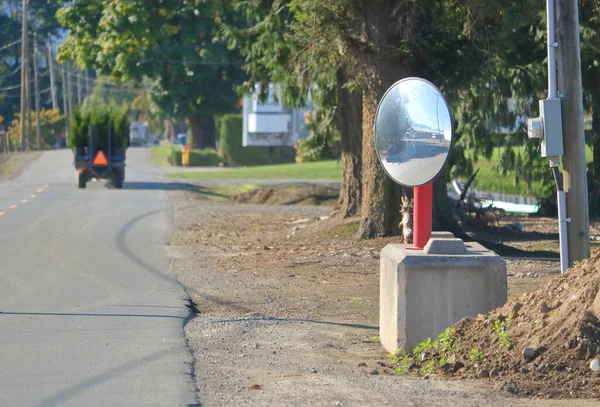 A curved, wide angle mirror has been set-up on a public road to ensure additional safety for employees using warehouse vehicles transporting goods.