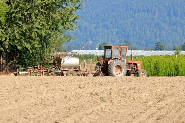 古いトラクターは まだ便利で実行して 背中に肥料が付いている樽で耕されたフィールドに座っています — ストック写真