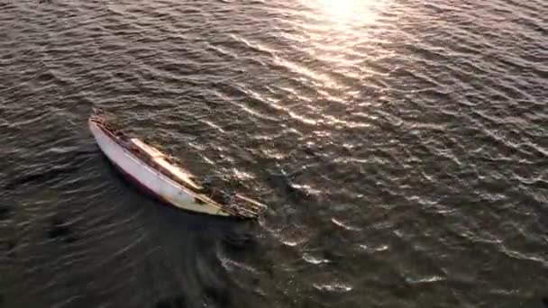 Drone Shot of Small Boat Wreck along the Shore with Sun Reflecting in the Water — Vídeo de stock