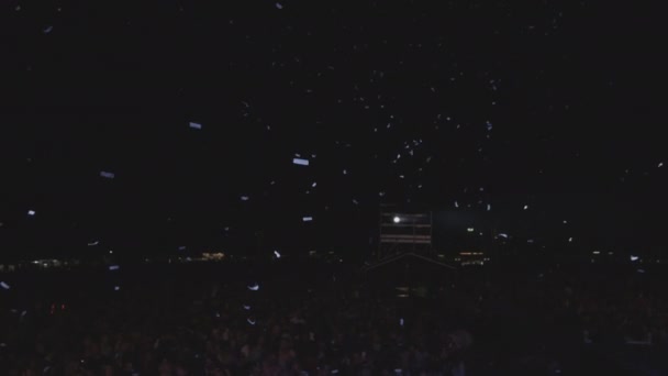 Confetti lezuhan az égből egy éjszakai koncert alatt, tele közönséggel. — Stock videók