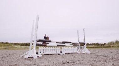 Ata binen ve çitin üzerinden atlayan kadın Paddock 'ta