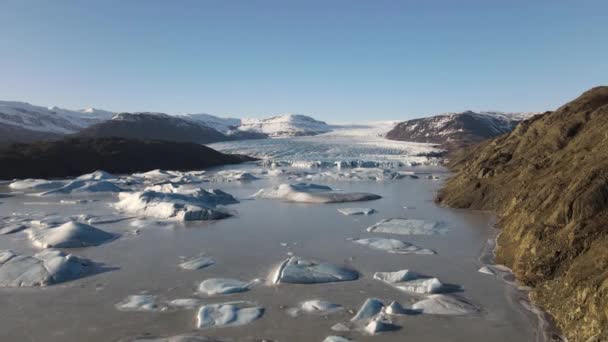 Drönare över frusen sjö till glaciär under blå himmel — Stockvideo