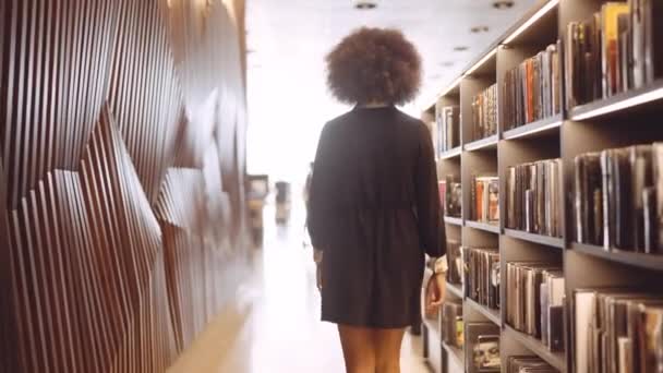 図書館を歩く若い女性 — ストック動画