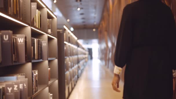 Joven mujer eligiendo libro de librería — Vídeos de Stock