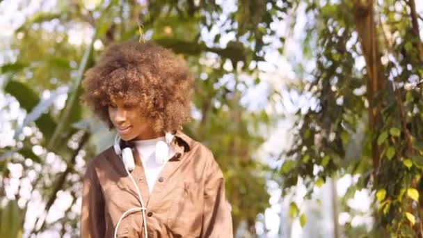 Mujer joven explorando jardines botánicos iluminados por el sol — Vídeos de Stock