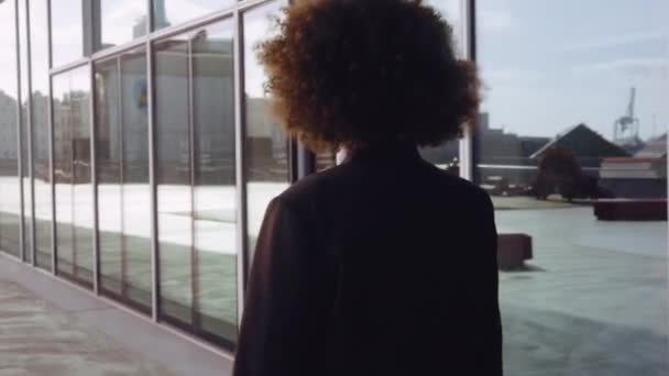 Empresária com cabelo afro andando fora do escritório moderno — Vídeo de Stock