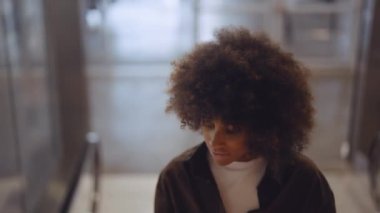 Yürüyen merdivende gülümseyen ve kaydıran kadın.