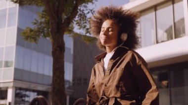 Şehirdeki kulaklıklarından müzik eşliğinde kaybolmuş bir kadın.