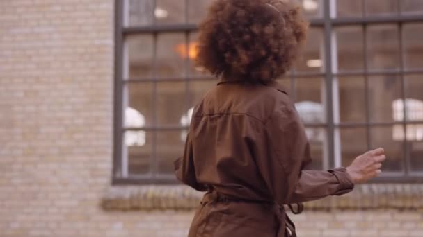 Женщина танцует по улице под музыку в наушниках — стоковое видео