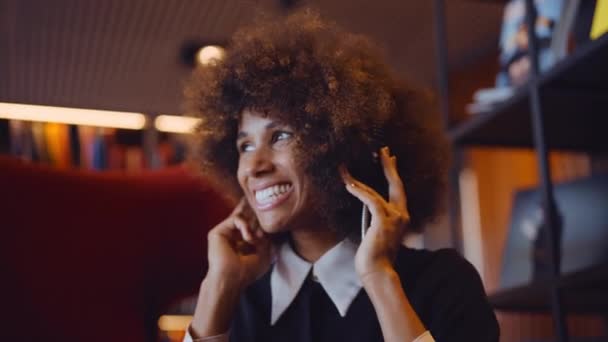 Женщина улыбается под музыку через наушники — стоковое видео