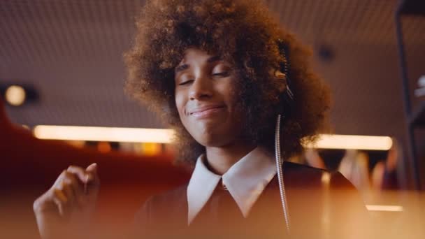 Kvinna med afro lyssnande att spela in spelare med hörlurar — Stockvideo