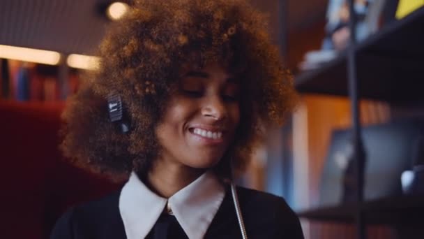 アフリカの髪を持つ女性は、ヘッドフォンで音楽を聴く — ストック動画