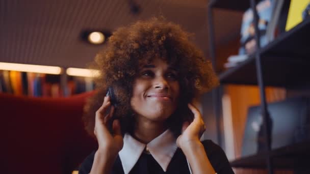 Mujer joven riendo y escuchando música a través de auriculares — Vídeos de Stock