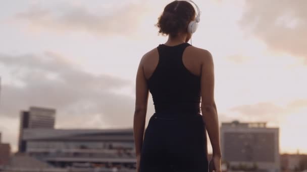 Mujer en ropa deportiva mirando a la ciudad después de una carrera — Vídeo de stock