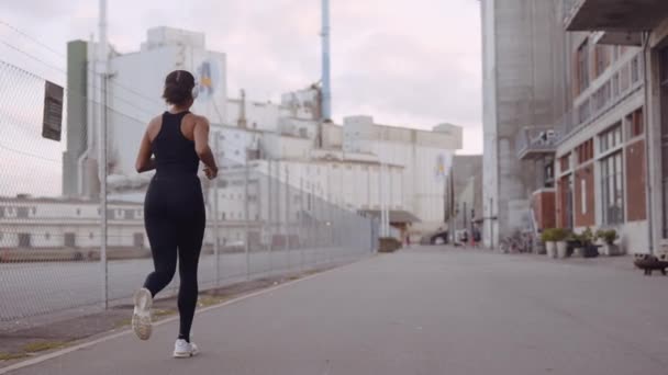 Mujer joven en ropa deportiva negra trotando a lo largo del puerto — Vídeos de Stock