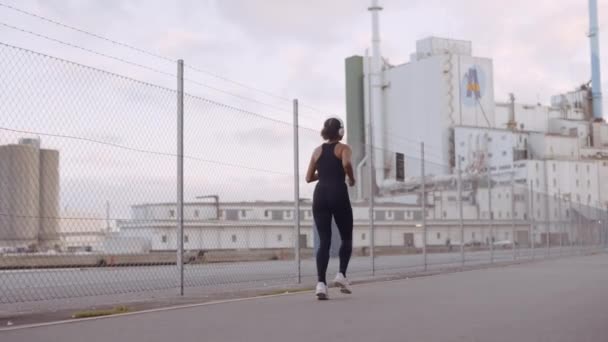 Mladá žena v černém sportovním oblečení jogging podél přístavu — Stock video