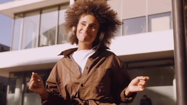 Kobieta z afro zagubiony w muzyce z jej słuchawek w mieście — Wideo stockowe