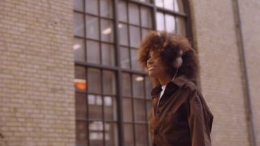 Kadın kulaklıkla müzik eşliğinde dans ediyor.