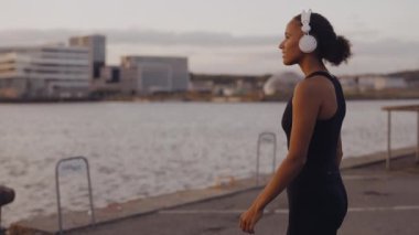 Güneş doğarken kulaklıklı kadın ve siyah spor giyim.
