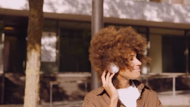 Frau bewegt sich über Kopfhörer auf Stadtbank zur Musik — Stockvideo