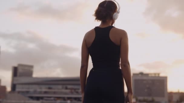 Mujer en ropa deportiva mirando a la ciudad después de una carrera — Vídeos de Stock