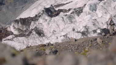 Buzulun yanındaki Rocky Hill 'de gitar çantası taşıyan gezgin.
