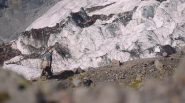 Buzulun yanındaki Rocky Hill 'de gitar çantası taşıyan gezgin.