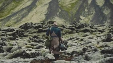 Gitar kılıfıyla Kayaların Üzerinde Yürüyen Adam