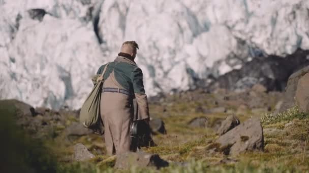 Reisender trägt Gitarrenkoffer auf Rocky Hill neben Gletscher — Stockvideo