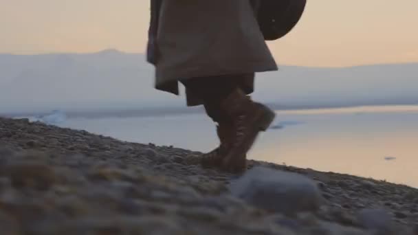 Hombre con botas caminando a través del paisaje frío del atardecer — Vídeos de Stock