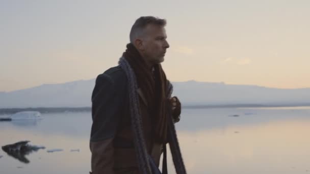 Man wandelend in sjaal en grote jas in het IJslandse landschap — Stockvideo