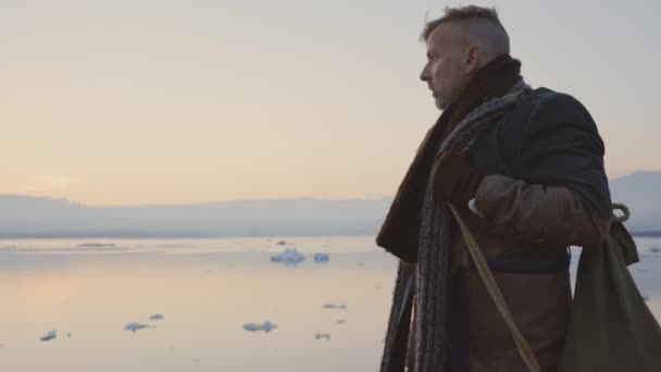 Hombre caminando en bufanda y abrigo grande en paisaje islandés — Vídeos de Stock