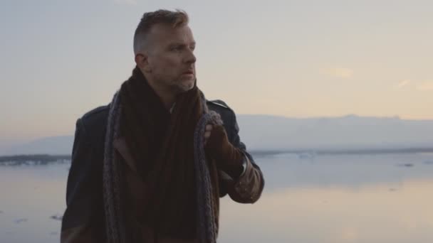 Muž kráčející v šále a velký kabát v islandské krajině — Stock video