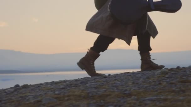 Man dragen gitaar geval door koude zonsondergang landschap in IJsland — Stockvideo