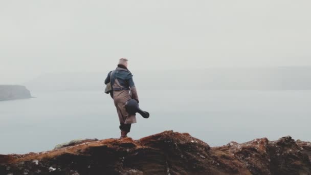 Reisender Mann geht auf Felsen mit Blick auf Flusstal — Stockvideo