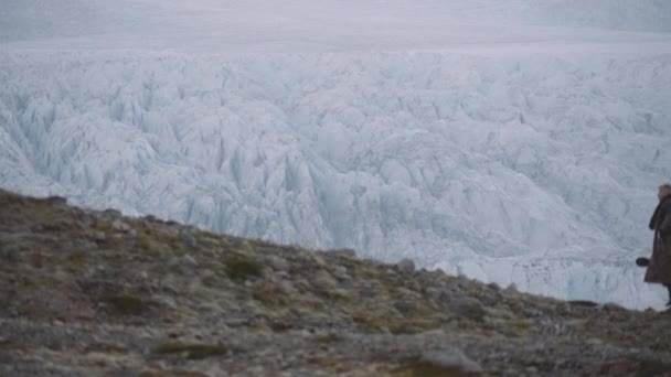 Muž kráčející do kopce vedle ledovce na Islandu — Stock video