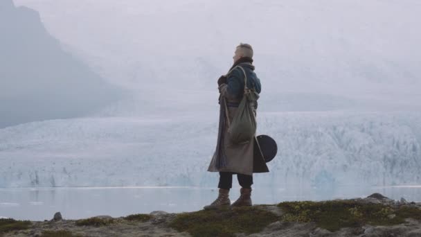 Hombre de pie junto al glaciar en el paisaje islandés — Vídeos de Stock